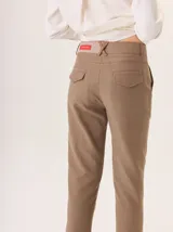 Pantalón de vestir azul marino, corte cigarette con pierna angosta y abertura en el bajo. Presenta costuras en contraste color beige y un botón marrón en la cintura.