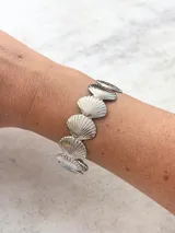 Brazalete plateado compuesto por eslabones en forma de caracolas con relieve y textura brillante.