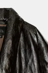 Cazadora acolchada Zara de efecto piel en color negro, con cuello en pico, manga larga, bolsillos delanteros y cierre frontal cruzado con botón.
