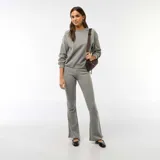 Pantalón de corte flare confeccionado en tejido de punto suave color gris, con cintura elástica y ajuste entallado en la parte superior que se ensancha hacia el ruedo.