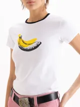 Remera blanca de manga corta, con ribetes negros en el cuello y estampa frontal de una banana estilo pop art.