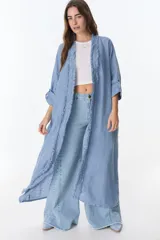 Kimono largo de lino color azul claro, con cuello abierto y detalles de flecos en los bordes. Mangas 3/4 con presilla y botón para ajustar.