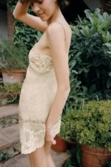 Vestido corto semitransparente de organza con escote en pico y tirantes finos. Presenta aplicaciones de bordados florales a contraste y detalles de cintas horizontales.