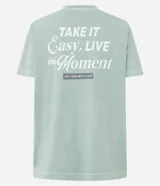 Remera de algodón con calce oversized, cuello redondo y mangas cortas. Presenta un diseño minimalista con un pequeño estampado de texto en el pecho y un acabado lavado en color verde menta.
