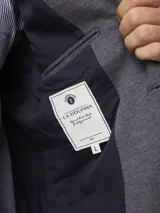 Blazer de piqué en color azul, con solapa clásica, cierre frontal de dos botones y bolsillos laterales de parche.