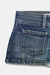 Shorts mini de denim azul oscuro con efecto lavado, tiro bajo, trabillas, cinco bolsillos (incluyendo bolsillos de plastrón en el delantero) y cierre frontal de cremallera y botones metálicos.