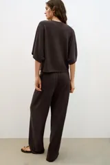 Pantalón rústico color marrón oscuro, de tiro alto, con cintura elástica y cordón ajustable, y pierna ancha.