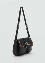 Bolso de hombro de cuero bovino en color negro con detalles en contraste color beige. Presenta un diseño con bolsillos tipo cargo en el frente, cierre de solapa con hebilla decorativa y cierre principal de cremallera. Incluye asa ajustable.