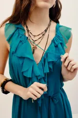 Vestido largo color verde turquesa, confeccionado en gasa con forrería a tono. Posee escote en V profundo con volados, sin mangas, y corte en la cintura con lazo ajustable.