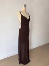 Vestido corto de microtul color marrón con diseño de doble capa, que incluye una base opaca y una capa exterior semitransparente. Presenta escote drapeado, tirantes finos y un ajuste ceñido al cuerpo con efecto fruncido lateral.