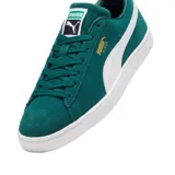 Championes Puma modelo Suede Classic, confeccionados en gamuza de color negro con la icónica franja lateral en blanco y el logotipo de la marca impreso en dorado metalizado en el lateral. Suela de goma texturizada en color blanco.