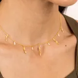 Collar dorado con cadena fina y dijes colgantes de perlas barrocas y piezas irregulares con textura.