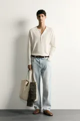 Remera polo de manga larga y calce regular fit en color blanco off-white, confeccionada en mezcla de algodón y lino, con cuello redondo y cartera con botonadura frontal.