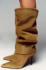 Bota de tacón alto de serraje color camel, con caña alta y diseño de calce fácil. Presenta tacón fino y punta.