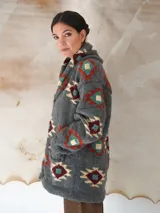Saco tejido a mano de color negro, con diseño geométrico multicolor, cuello smoking y cierre frontal con dos botones.