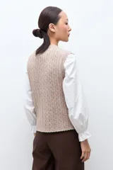 Chaleco de punto con textura acanalada, color tostado melange, con cuello redondo y cierre frontal de botones.