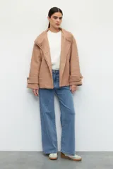 Tapado corto color beige de tejido grueso con cuello alto, cierre frontal con botones grandes veteados y bolsillos delanteros.