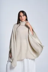 Poncho tejido color beige, con cuello alto y corte asimétrico.