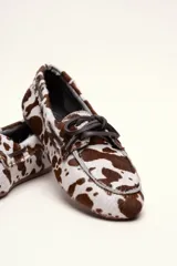 Mocasín tipo boat shoe color marrón, confeccionado en cuero, con cordones de cuero marrón y cordones decorativos azules.