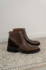 Bota corta de cuero marrón con panel trasero de gamuza en tono más oscuro, suela de goma negra y taco cuadrado bajo.