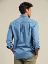 Camisa celeste de manga larga con cuello abotonado y bolsillo en el pecho.