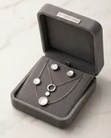 Collar de cadena fina de acero con dije colgante compuesto por dos círculos entrelazados, uno de acero liso y otro con incrustación de nácar en el centro.