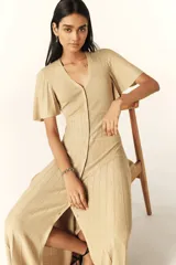 Vestido largo dorado de punto con mangas cortas con volantes, escote en V y cierre frontal con botones.