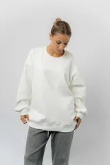Buzo oversize de cuello redondo, confeccionado en algodón suave con interior frizado. Presenta un diseño de líneas simples, corte relajado y mangas largas con puños ajustados.