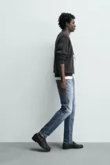 Pantalón de jean corte slim fit, color gris con efecto lavado. Presenta diseño de cinco bolsillos, cierre frontal con cremallera y botón, y tejido elástico.