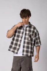 Camisa de manga corta de popelina cuadrillé en tonos marrón, blanco y gris, con diseño boxy fit, cuello camisero, cierre frontal de botones, bolsillo en el pecho con detalle bordado y dobladillo recto.
