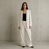 Blazer oversize color beige con diseño de raya diplomática, solapas clásicas, cierre de un solo botón y bolsillos delanteros con solapa.
