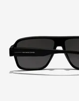 Lentes de sol unisex Hawkers modelo Parlay, con montura cuadrada negra y lentes grises.
