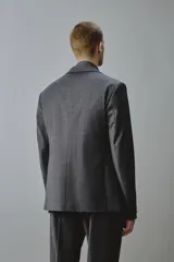 Blazer gris oscuro de corte regular fit con diseño de raya diplomática, confeccionado con mezcla de lana. Presenta solapas de muesca, cierre frontal de dos botones, bolsillos con solapa en la cadera y un bolsillo de vivo en el pecho.