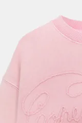 Sudadera de cuello redondo y manga larga, con efecto lavado y detalle de texto bordado a tono en el frente. Presenta puños y ruedo en rib.