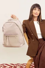 Mochila color beige, combinada con tela tipo impermeable y detalles en simil cuero. Tiene gran tamaño, asas combinadas, bolsillos al frente y compartimiento para notebook de 15".