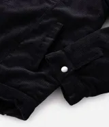 Campera de pana negra con cuello de sherpa blanco, cierre frontal por cremallera y bolsillos delanteros con solapa y botón. Presenta forro interno de sherpa para mayor calidez.