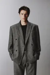 Blazer de corte relajado confeccionado en tejido con lana, con diseño de espiga. Presenta cuello con solapas de muesca, cierre frontal de botonadura cruzada, bolsillos de vivo en el pecho y bolsillos de solapa en la cadera.