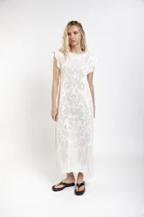 Vestido largo de crochet color crudo, con mangas cortas con volados y aberturas laterales, confeccionado en tejido calado de algodón con diseño ornamentado.