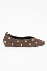 Chatita de gamuza color marrón con detalle de tachas metálicas doradas distribuidas por toda la superficie. Presenta una tira pequeña en el talón y diseño de punta redondeada.