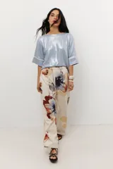 Blusa de manga corta con brillo, color celeste metalizado, con puños anchos ribeteados en color crema.