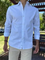 Camisa de manga larga color blanco, de corte clásico y cierre frontal con botones.
