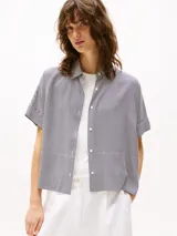 Camisa de manga corta con cuello clásico y cierre frontal con botones. Diseño a rayas verticales en blanco y negro.