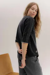 Buzo básico de lambswool color gris oscuro, con escote en V y mangas 3/4. Presenta un fit amplio y tajos laterales. Los puños tienen un detalle de ribete en color celeste y amarillo.