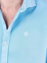 Camisa lisa de hombre color celeste, confeccionada en 100% algodón con acabado vintage. Presenta corte regular fit, cuello italiano, cierre con botones, manga larga con puño simple y logo bordado en el pecho.