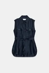 Chaleco azul marino confeccionado en hilatura con lino, con cuello solapa, manga sisa y trabillas en los hombros. Cuenta con bolsillos de plastrón con solapa en el delantero, cinturón ajustable del mismo tejido y bajo asimétrico con aberturas laterales. Cierre frontal con botones.