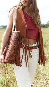 Pantalón de jean blanco con corte acampanado, cintura alta, detalles trenzados y aplicaciones de cuero en la parte inferior.