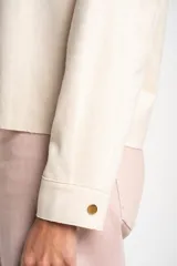 Camisa tipo sobrecamisa oversize color crudo, confeccionada en tejido de gamuza vegana con cierre frontal de botones metálicos y cuello clásico.