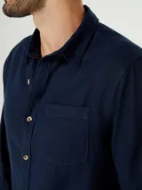 Camisa de manga larga en color gris, con cuello clásico, cierre frontal de botones y un bolsillo en el pecho.