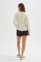 Blusa blanca de viscosa, con cuello en V, detalles de frunces en el frente, botones decorativos y mangas largas holgadas.