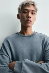 Sudadera de corte relaxed fit confeccionada en tejido de algodón con interior de rizo. Presenta cuello redondo, manga larga y acabados en rib, con un acabado de efecto lavado que le otorga una apariencia única.